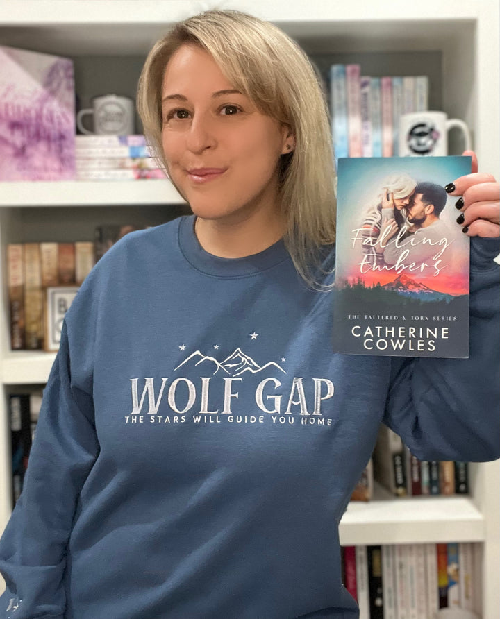 a woman holding up a book in front of a bookshelf